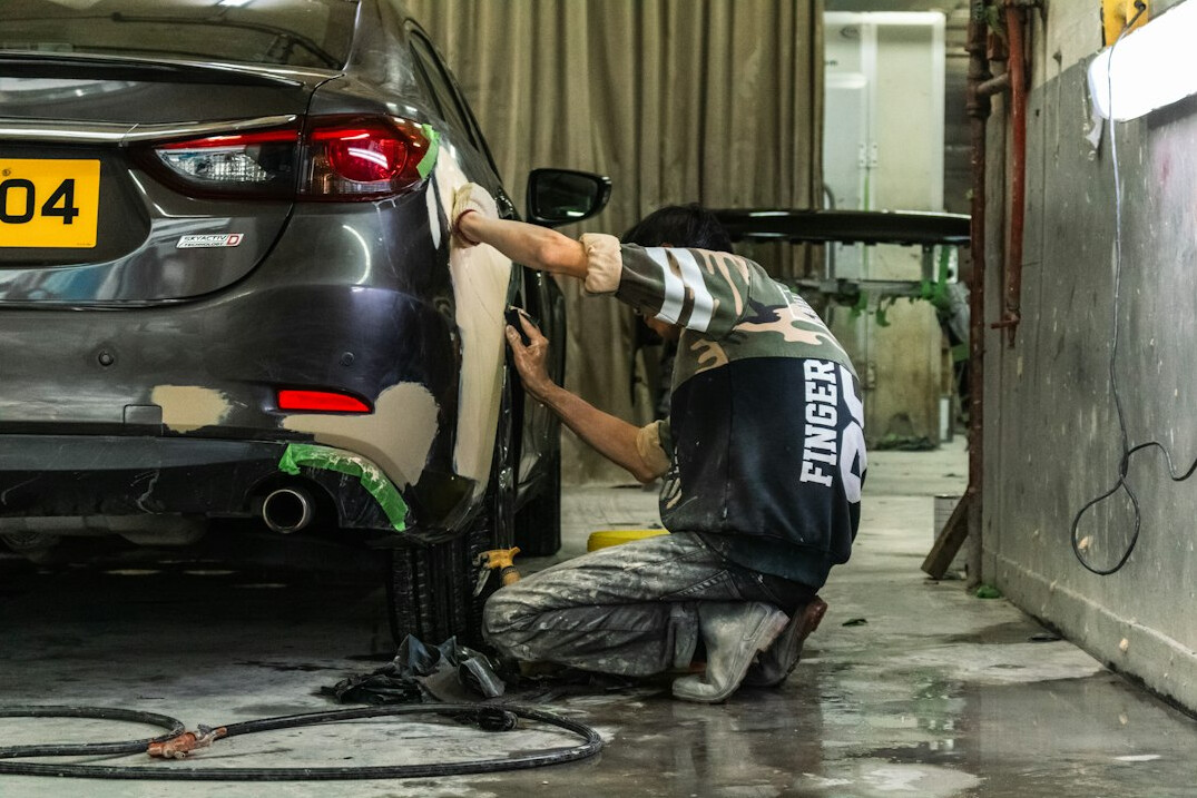 Mechanic examining a car body panel in a workshop